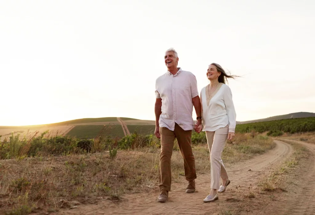 Older couple walking hand in hand along a countryside path